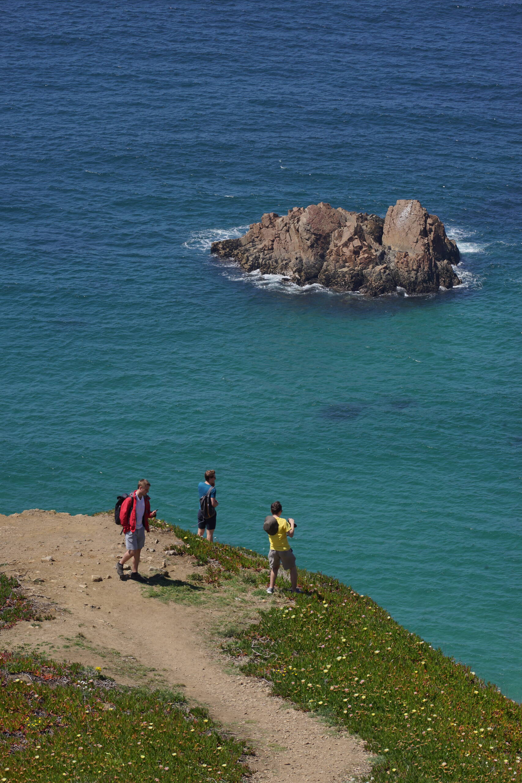 An image of 3 guys and a rock.